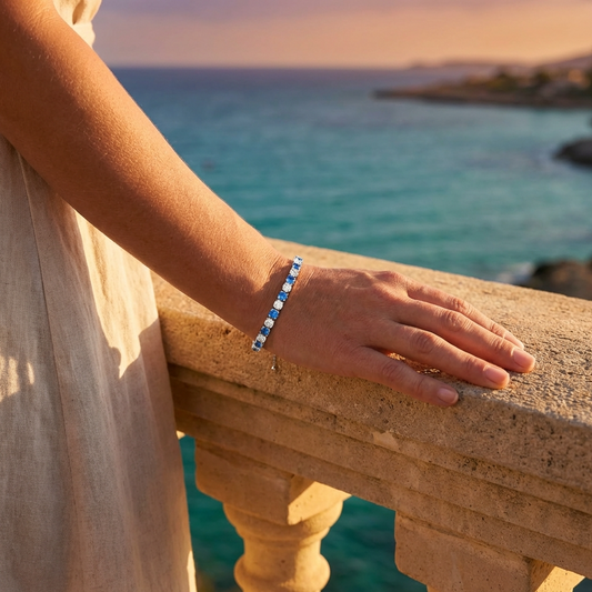 Bracciale tennis argento 925 indossato al polso donna con zirconi azzurri, elegante al tramonto sul mare